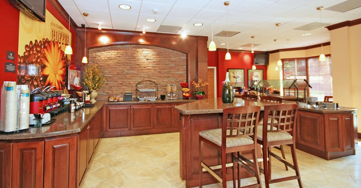This image features a cozy coffee bar with a decorative wall and a comfortable seating area. The setting is warm and inviting, encouraging guests to gather, socialize, and enjoy coffee together.